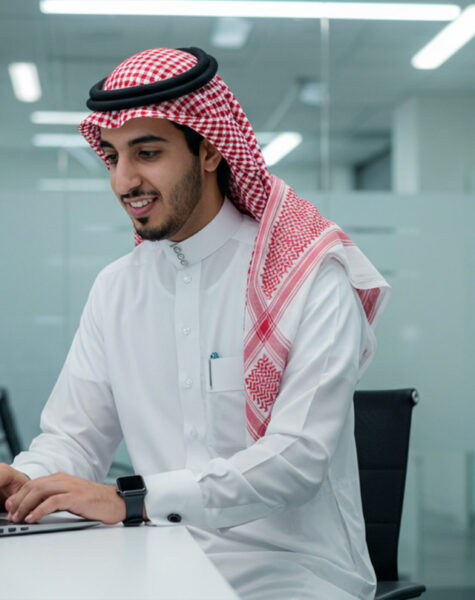 young-man-wearing-saudi-dress-sitting-desk-with-computer-front young-man-wearing-saudi-dress-sitting-desk-with-computer-front